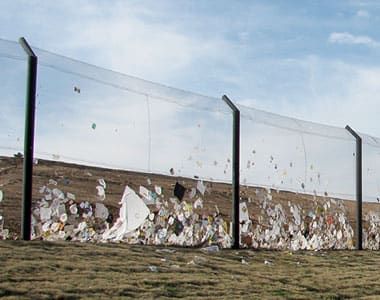 A tall stationary litter fence catching lots of wind-blown trash.